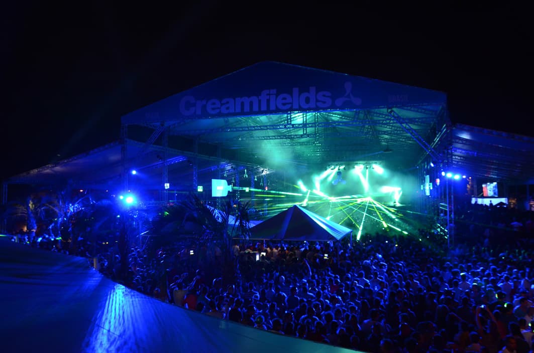 A night-time Creamfields crowd facing a lit stage