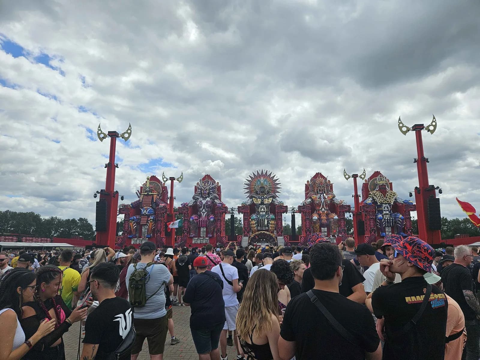 The five giant warrior statues of the Defqon.1 2024 mainstage over a crowd with flags