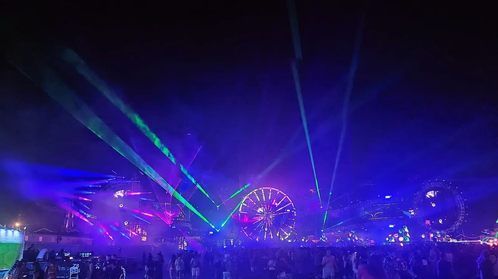 The EDC Las Vegas ferris wheel at night surrounded by lasers cutting through the sky