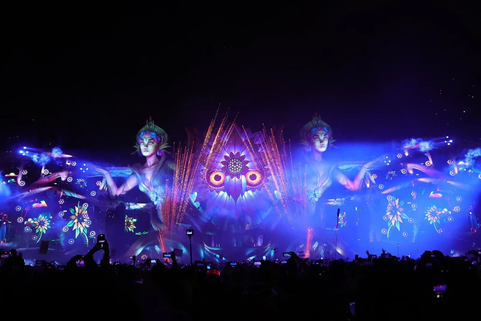 The giant kineticFIELD owl main stage at EDC Mexico glowing purple and orange with fireworks over the crowd