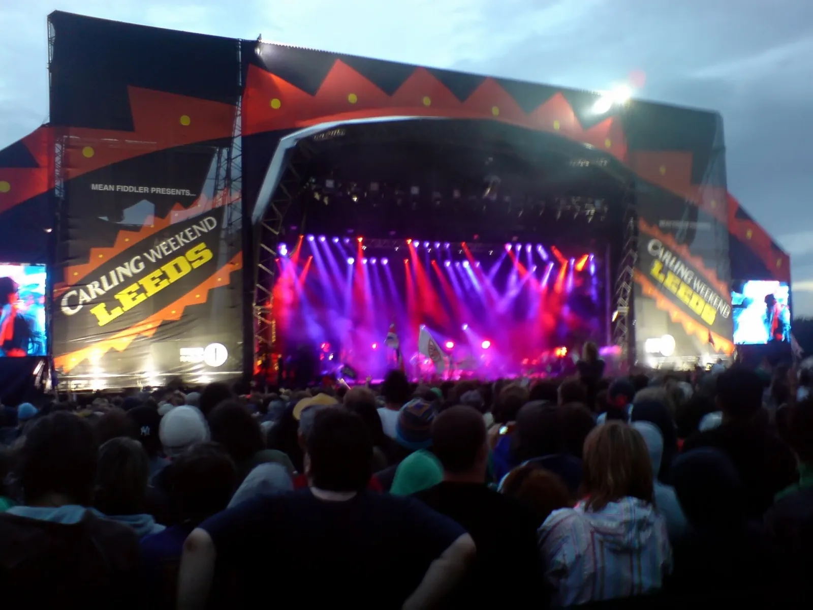 The Leeds Festival Main Stage lit purple at dusk in 2006, with the crowd silhouetted in front