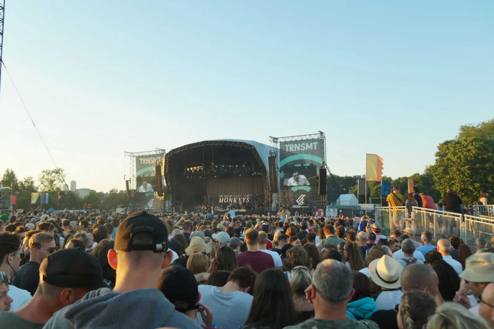 A golden-hour crowd facing the TRNSMT main stage on Glasgow Green as Arctic Monkeys play