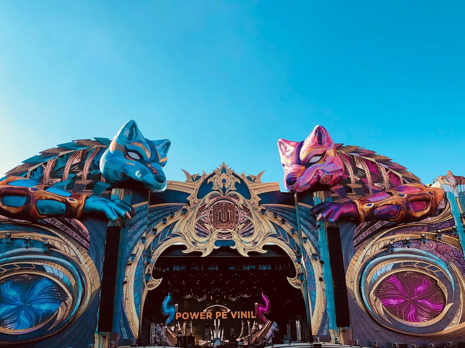 The UNTOLD mainstage with two giant wolf sculptures under a clear blue sky