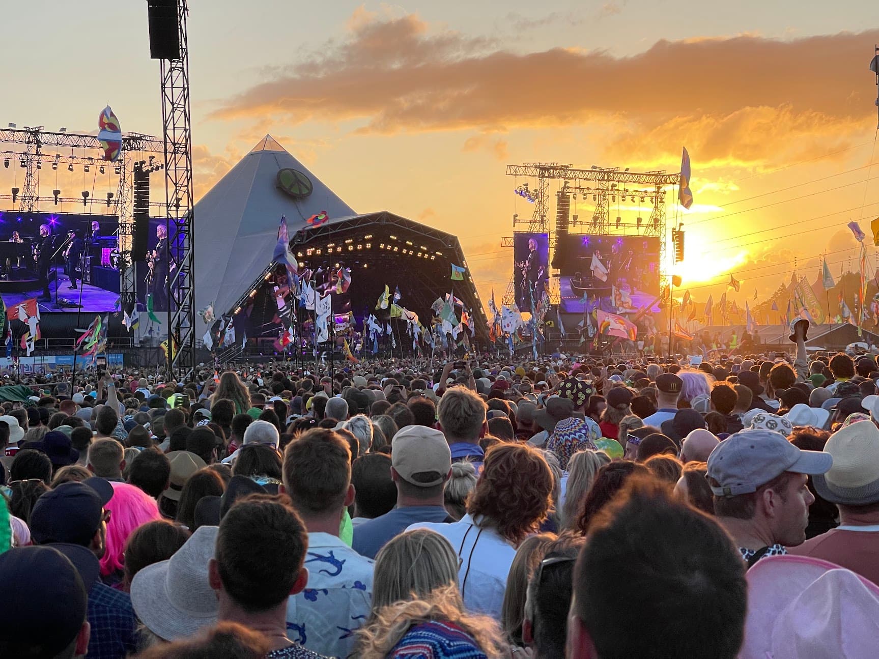 Crowd watching the Pyramid Stage at Glastonbury as the sun sets